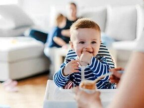 Bebé en su silla comiendo alimentos sólidos