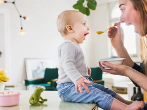 Bebé de 10 meses sentado comiendo con mamá