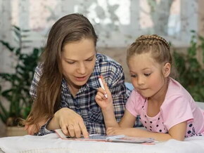 Mamá explicando a su hija por medio de un libro.