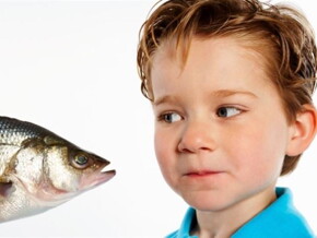 Un niño pequeño observando un pescado con curiosidad.