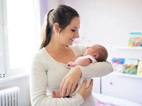 Mamá primeriza alzando en brazos a su bebé recién nacido.