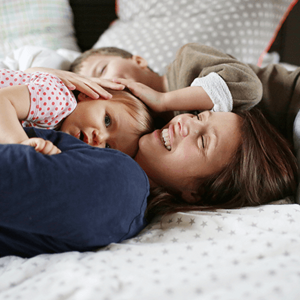 Una mujer y dos niños felices acostados en una cama.