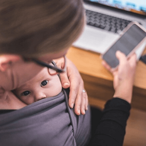 madre trabajando con su hijo en brazos