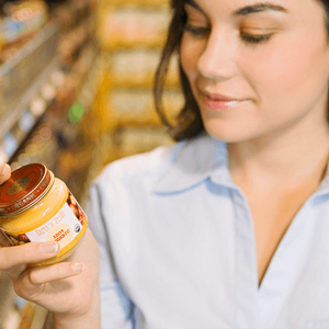 Mujer leyendo etiqueta nutricional con un frasco de colado para bebes