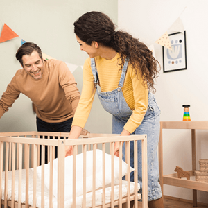 Un hombre y una mujer preparan la cuna del bebe