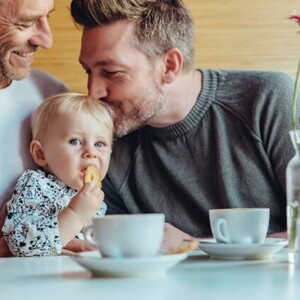 Niña comiendo galletas para bebés con su papá y abuelo.