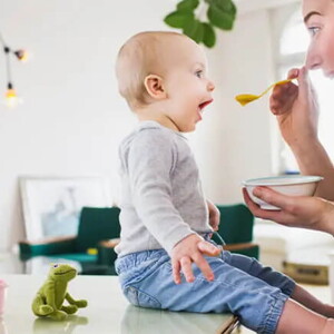 Bebé de 10 meses sentado comiendo con mamá