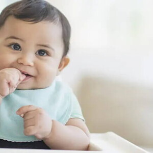 Bebé de 9 meses sentado sonriendo.