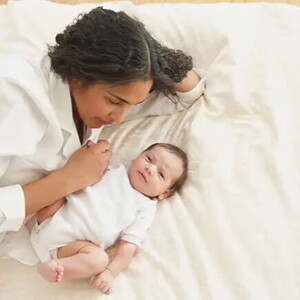 Mamá acostada con su bebé de tres meses.