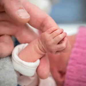 Mamá cogiendo la mano de su bebé de un mes.