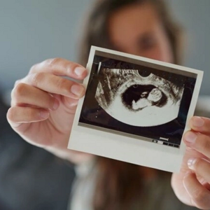 Mujer sosteniendo una imagen por ecografía