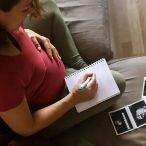 Mamá con un cuaderno mirando la ecografía de su embarazo múltiple.