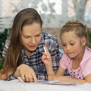 Mamá explicando a su hija por medio de un libro.