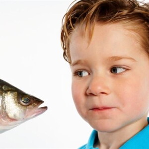 Un niño pequeño observando un pescado con curiosidad.