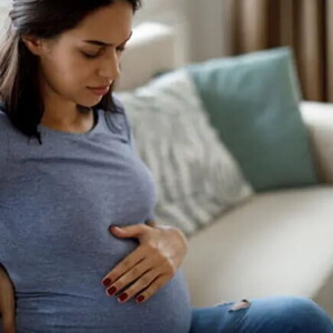 Mamá tocando el vientre y la espalda sintiendo molestia.