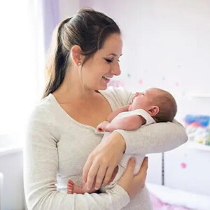 Mamá primeriza alzando en brazos a su bebé recién nacido.