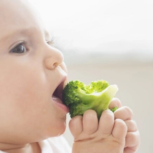 Imagen de un adorable bebé disfrutando de una comida saludable mientras come brócoli