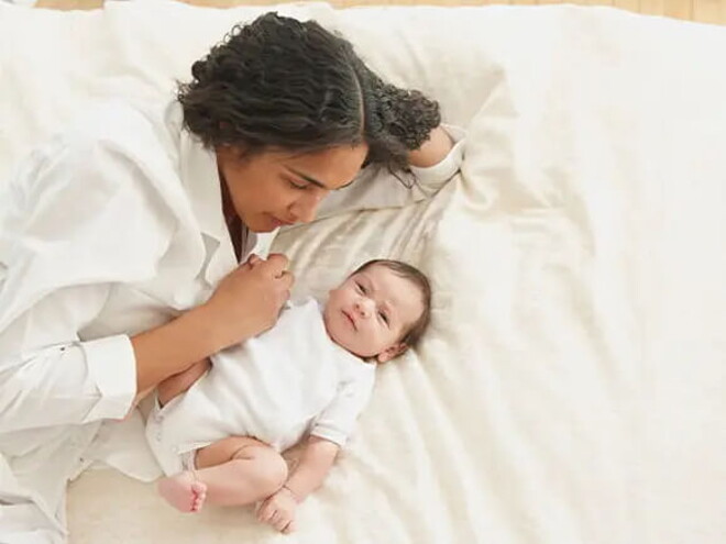 Mamá acostada con su bebé de tres meses.