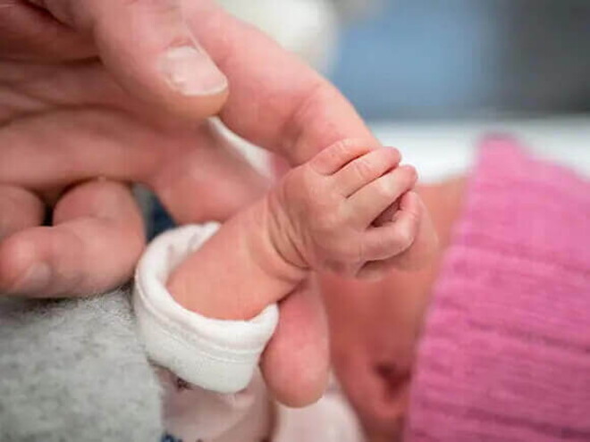 Mamá cogiendo la mano de su bebé de un mes.