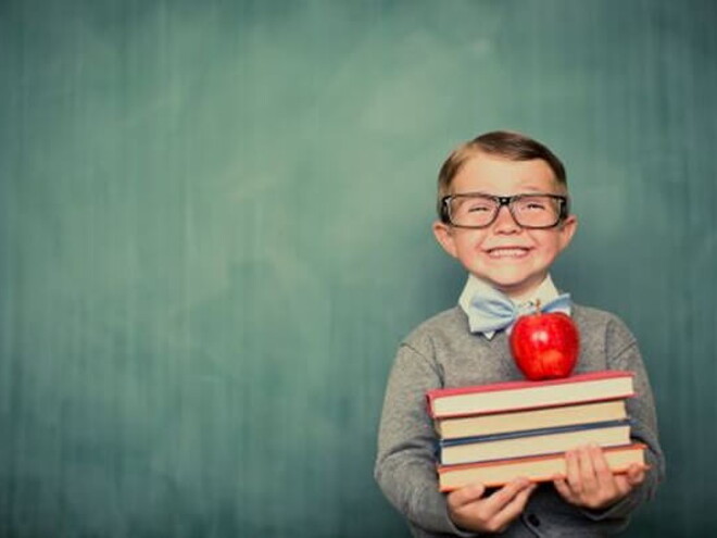 Niño sonriendo con libros en la mano.