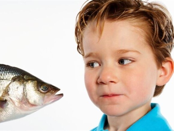 Un niño pequeño observando un pescado con curiosidad.