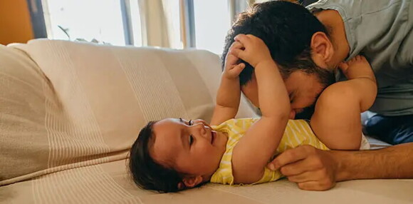 Papá jugando con su bebé de cinco meses.