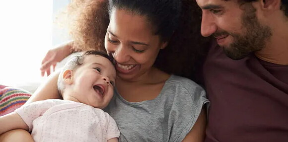 Bebé de cinco meses sonriendo con sus papás.